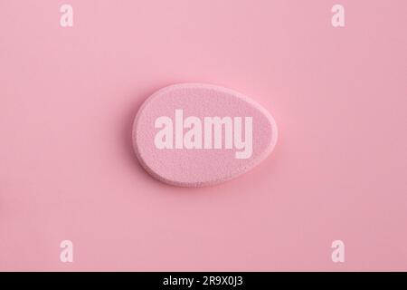 Éponge cosmétique en forme d'œuf sur fond rose. Vue de dessus Banque D'Images