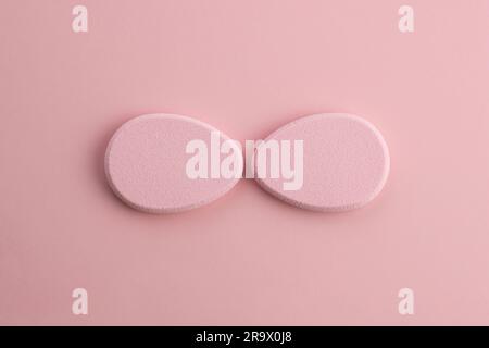 Éponge cosmétique en forme d'œuf sur fond rose. Vue de dessus Banque D'Images