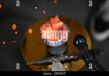 Sindelfingen, Allemagne. 29th juin 2023. Des morceaux de charbon pour chauffer le tabac se trouvent sur un tuyau d'eau de nargua dans un bar de nargua. Les bars de shisha dominent de plus en plus le paysage urbain dans de nombreuses villes. Mais le marché du narguilé souffre de trop de règles et de bureaucratie, critiquant les jeunes libéraux du Bade-Wurtemberg. (À dpa "les jeunes libéraux critiquent la bureaucratie pour les barres de nargua") Credit: Bernd Weißbrod/dpa/Alamy Live News Banque D'Images