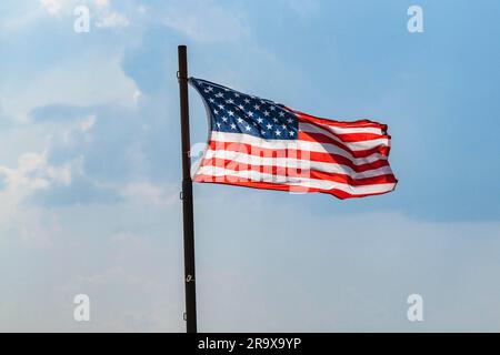 Le pavillon de l'USA sur un mât agitant au vent sur un ciel bleu Banque D'Images