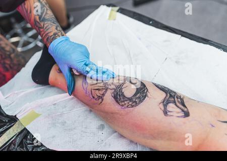 gros plan d'un client qui obtient un nouveau tatouage sur une jambe dans le studio d'art. Photo de haute qualité Banque D'Images