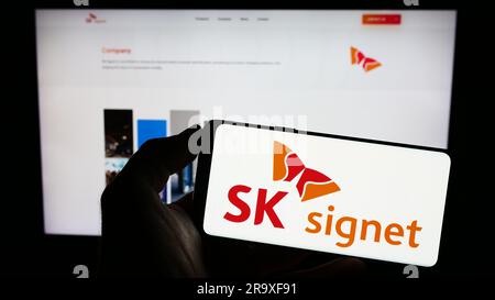 Personne tenant un téléphone portable avec le logo de la société coréenne de charge d'EV SK Signet à l'écran devant la page Web d'affaires. Mise au point sur l'affichage du téléphone. Banque D'Images