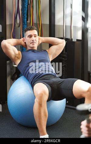 homme de fitness mature faisant des croquons abdominaux à la salle de gym sur un pilates ball Banque D'Images