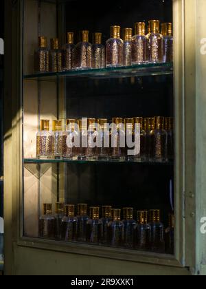 Gros plan des bouteilles de verre à l'attar ou à parfum dans un présentoir dans un magasin. Lumière du soleil sur quelques bouteilles. Banque D'Images