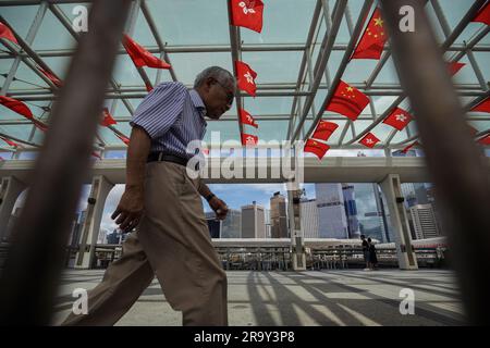 Hong Kong, Chine. 27th juin 2023. Un homme passe devant les drapeaux de la Chine et de Hong Kong sur un quai. À l'approche de l'1 juillet, Hong Kong se prépare à marquer l'anniversaire de son transfert de la Grande-Bretagne à la Chine, commémorant l'année 26th qui a suivi le transfert de souveraineté. Dans toute la ville, les drapeaux de la Chine et de Hong Kong ont été suspendus, symbolisant l'importance historique de cet événement. (Credit image: © Michael Ho Wai Lee/SOPA Images via ZUMA Press Wire) USAGE ÉDITORIAL SEULEMENT! Non destiné À un usage commercial ! Banque D'Images