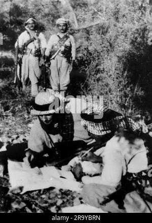 Un groupe d’Arabes dont deux étudient une carte, faisant partie d’un groupe décrit comme des « brigands » (membre d’un gang qui tend des embuscades et vole des gens dans les forêts et les montagnes). Cette photographie est tirée d'un album de photographies de clichés principalement, c1937, pendant l'occupation de la Palestine par l'armée britannique. La Grande-Bretagne administra la Palestine au nom de la Société des Nations entre 1920 et 1948, période appelée « mandat britannique ». Banque D'Images