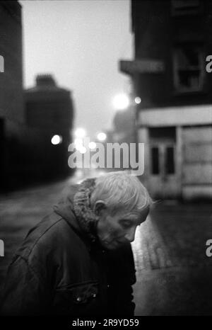 East End London années 1970, Brick Lane un vieux résident masculin se plie en double avec l'âge et les promenades froides dans la rue en fin de soirée. Tower Hamlets, Londres, Angleterre 1976. ANNÉES 70 ROYAUME-UNI HOMER SYKES Banque D'Images