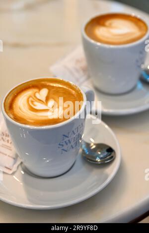 Deux tasses de café avec mousse de lait et une cuillère à café sur la soucoupe Banque D'Images