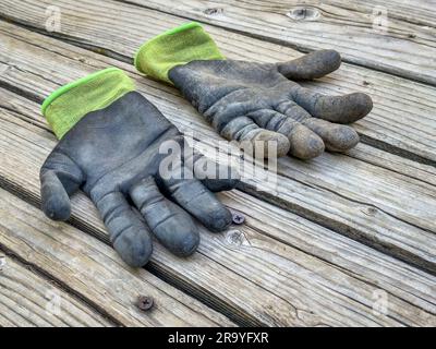 une paire de gants de jardin en bambou sales et bien utilisés sur une terrasse rustique en bois Banque D'Images