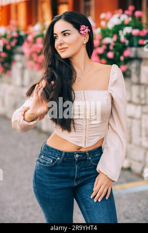 Portrait romantique d'une jolie jeune femme avec de longs cheveux noirs, portant un corset rose chemisier Banque D'Images