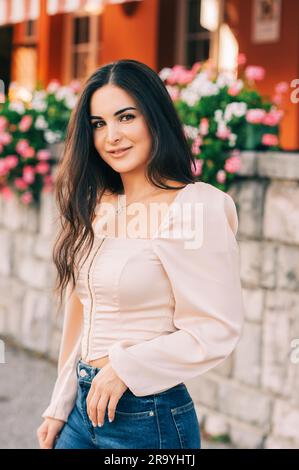 Portrait romantique d'une jolie jeune femme avec de longs cheveux noirs, portant un corset rose chemisier Banque D'Images