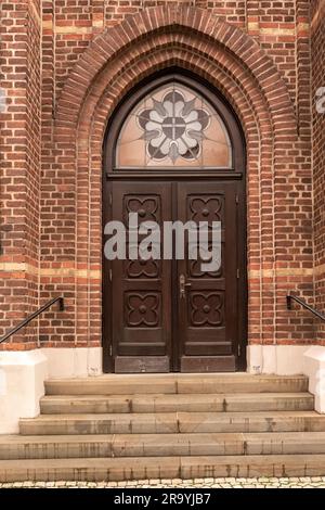 Cette image présente une porte en bois double ornée avec un briquetage complexe et une fenêtre en verre voûté Banque D'Images