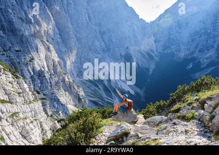 Impressionnante échelle de montagnes dans le parc national de Triglav, Slovénie. Femme sur via ferrata est assise sur un rocher et pointe vers le haut, vers le haut. Été, aventurier Banque D'Images