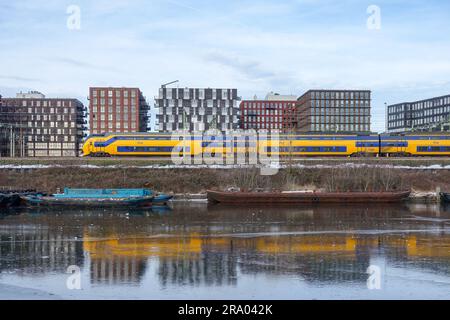 Train NS (pays-Bas) réfléchissant sur des canaux gelés à Amsterdam Banque D'Images