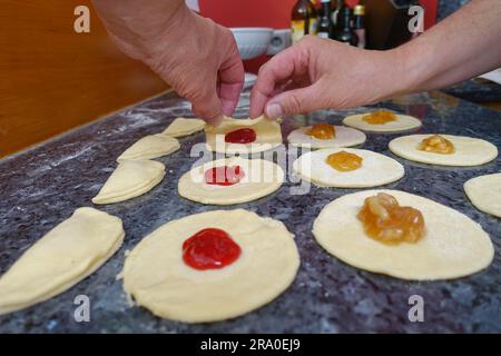 Cuisine souabe, Kraepfle du souabe supérieur avec Gsaelz, pâtisserie sucrée, préparation de beignets fourrés avec confiture, plier les morceaux de pâte avec de la confiture d'orange, plier Banque D'Images