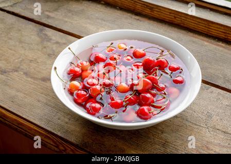 Des griottes dans une assiette de porcelaine sur le rebord en bois Banque D'Images