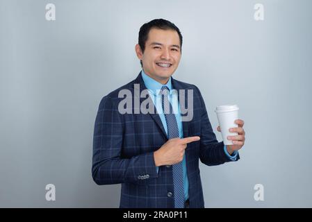 un jeune mexicain à la peau sombre sourit tout en pointant son doigt sur une tasse de café prête pour le marketing de travail d'affaires, une personne Banque D'Images