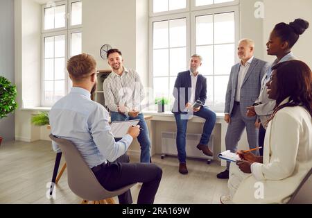 Dirigeant homme confiant parlant avec un groupe multiracial de travailleurs au pouvoir Banque D'Images