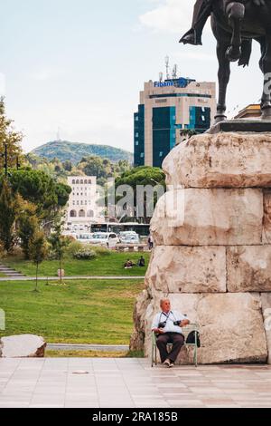 Un homme est assis devant le monument Skanderbeg – un héréo national qui a combattu les Ottomans – sur la place Skanderbeg, Tirana, Albanie Banque D'Images