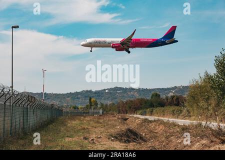 Un Airbus A321 de Wizz Air débarque au-dessus de la clôture du périmètre de l'aéroport international de Tirana, en Albanie Banque D'Images