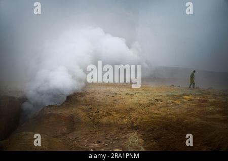 Une femme se tient près de geyser dans un désert brumeux en Bolivie Banque D'Images