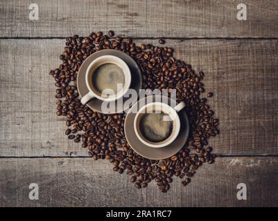 Dose en grand angle de tasses d'espresso sur des grains de café sur une table en bois. Banque D'Images