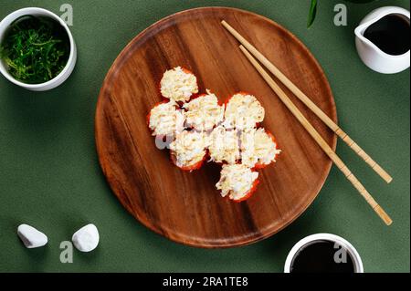 des petits pains à sushis asiatiques avec des chapeaux de fromage sur une assiette de bois Banque D'Images