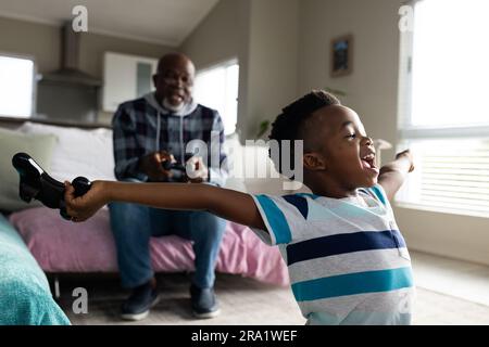 Grand-père et petit-fils afro-américains assis sur le canapé et jouant à des jeux vidéo Banque D'Images
