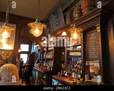 Intérieur de la maison publique Flask à Hampstead, Londres, montrant le bar historique, l'éclairage traditionnel, les étagères de boissons et les tableaux de menu. Banque D'Images