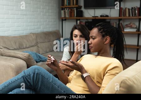 Jeune femme essayant de réconfort meilleure amie après avoir obtenu un test de grossesse positif à la maison. Colocataire à la maison, Afro-américaine femme est enceinte Banque D'Images