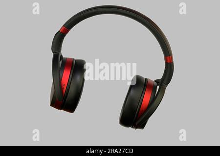 Casque stéréo sans fil. Casque sans fil noir et rouge. Écouteurs isolés sur fond gris avec un masque. Macro image horizontale, gros plan Banque D'Images