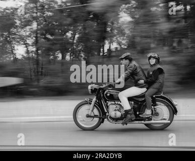 Homme et femme volant sur la route sur une moto avec l'arrière-plan flou Banque D'Images