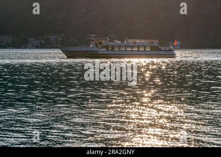 Un ferry sur le lac de Lugano arrive à Porto Ceresio, en Italie, de Morcote, en Suisse, au coucher du soleil Banque D'Images