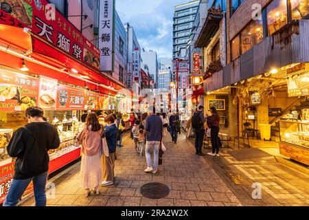 Il y a des stands de nourriture et des restaurants de part et d'autre de la rue piétonne principale bondée la nuit à Nankinmachi, dans le quartier chinois, à Kobe, au Japon. Banque D'Images