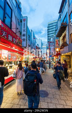 Il y a des stands de nourriture et des restaurants de part et d'autre de la rue piétonne principale bondée la nuit à Nankinmachi, dans le quartier chinois, à Kobe, au Japon. Banque D'Images