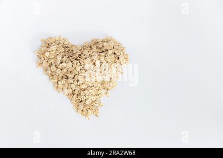 Flocons d'avoine formant un cœur sur fond blanc, image conceptuelle. Super nourriture riche en nutriments et qui peut être utilisé pour plusieurs recettes. Banque D'Images
