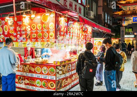 Grand coin de rue vendant des fast-foods chinois, dont des petits pains et des boulettes à la vapeur, devant un restaurant près de l'Eastern Gate, Chinatown à Kobe. Nuit. Banque D'Images