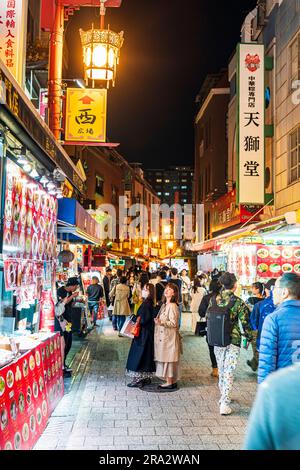 Chinatown à Kobe la nuit. Vue sur une petite rue piétonne remplie de gens qui erraient entre les stands de nourriture vendant la cuisine chinoise à emporter. Banque D'Images