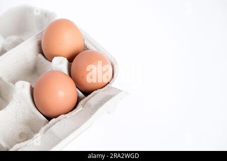Détail d'un carton d'œufs en carton recyclé ouvert avec quelques œufs à l'intérieur sur un fond blanc avec espace de copie. Banque D'Images