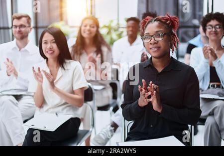 Objectif sélectif de la jeune femme d'affaires applaudissant avec des collègues interraciaux pendant le séminaire, bannière Banque D'Images