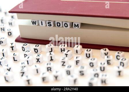 Mot sagesse écrit avec des lettres entre un livre pages fond blanc avec des lettres réparties autour de l'éducation lecture concept Banque D'Images