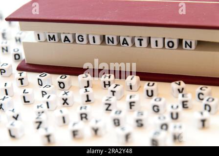 Mot imagination écrit avec des lettres entre un livre pages fond blanc avec des lettres réparties autour de l'éducation lecture concept Banque D'Images