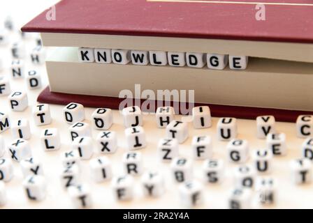 La connaissance de mot écrit avec des lettres entre les pages d'un livre fond blanc avec des lettres réparties autour du concept de lecture d'éducation Banque D'Images