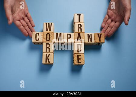 Les mots entreprise travaillent sur des cubes en bois sur fond bleu. Banque D'Images