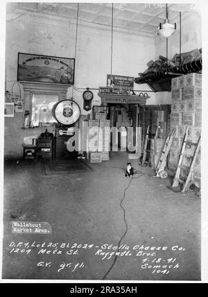 Photographie de l'intérieur marché du mur, D.P. 4, Lot 25, Bâtiment 2024- Stella Cheese Co.-Ruffetto Bros. G.V. gr. fl. Vue sur la zone de l'échelle dans un entrepôt à plafond élevé avec des boîtes, des chariots de manutention et un chat noir et blanc, du négatif 1041. Banque D'Images