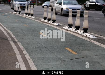 piste cyclable verte peinte sur la rue à côté des voitures avec des poteaux de sécurité (bornes en plastique, cycleuse, vélo, cycling) Banque D'Images