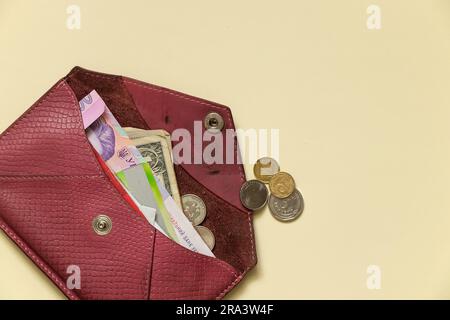 ouvrez le portefeuille pour femmes avec des dollars et hryvnia sur un fond beige clair gros plan Banque D'Images