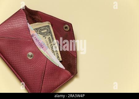 ouvrez le portefeuille pour femmes avec des dollars et hryvnia sur un fond beige clair gros plan Banque D'Images