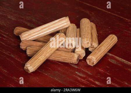 pile de chevilles sur fond rouge, chevilles utilisées pour joindre deux morceaux de bois, joint, menuiserie Banque D'Images