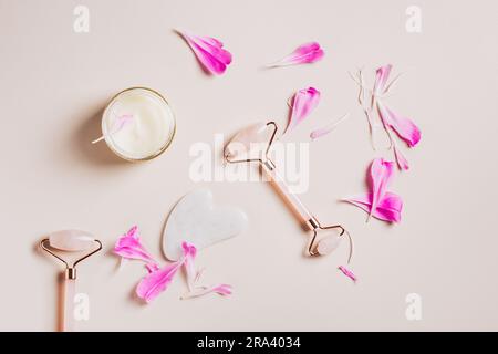 Ensemble d'accessoires de soin pour le visage et le cou sur fond rose. Rouleaux faciaux et gua sha. Banque D'Images